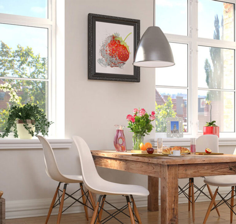 Table en bois dans une cuisine contemporaine, installée entre deux fenêtres blanches mixtes laissant entrer la lumière matinale sur les viennoiseries posées sur la table.