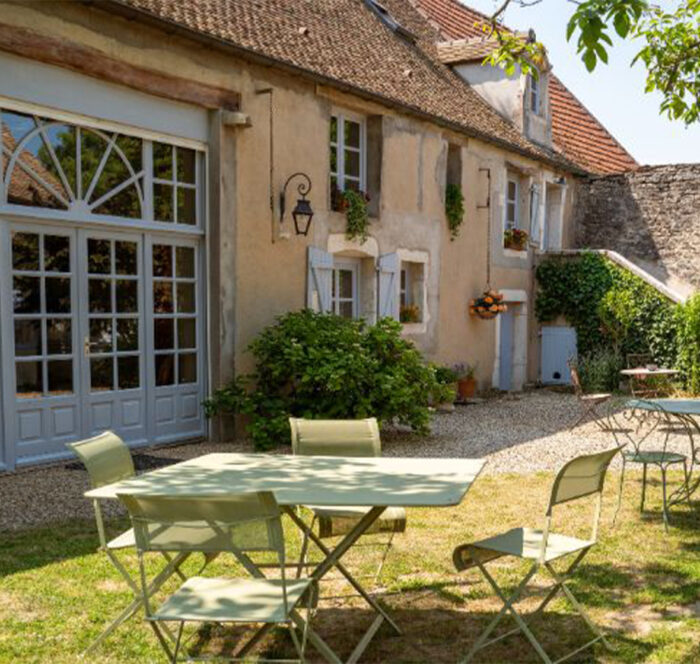 Vue extérieure d'une façade de maison de campagne en pierre à rénover en plan large avec aperçu du jardin