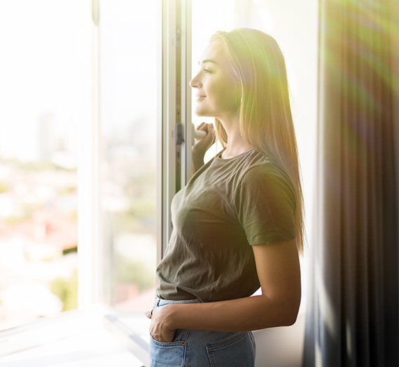 Femme devant une fenêtre blanche baignée de lumière