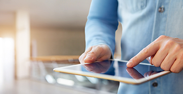 Zoom sur les mains d'un homme consultant internet sur sa tablette chez lui