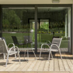 Baie vitrée coulissante aluminium donnant sur la terrasse d'une maison vers un jardin arboré