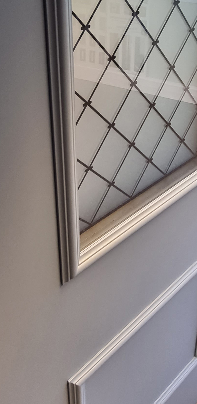 zoom sur le détail d'une porte aluminium prestige de la gamme tradition avec vue sur les moulures et le vitrage grille quadrille fabricant francais amcc