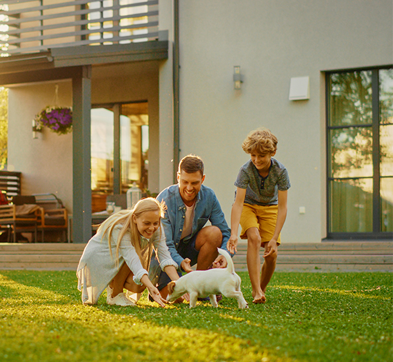Famille qui joue dans le jardin de leur maison avec un chien