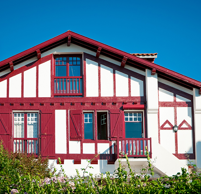 maison basque typique avec sa façade blanche à colombage rouge sur la zone de Etxe Vérandas fenêtres et portes