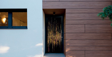 Vue extérieure d'une façade de maison actuelle avec une porte d'entrée contemporaine grand vitrage peint noire AMCC