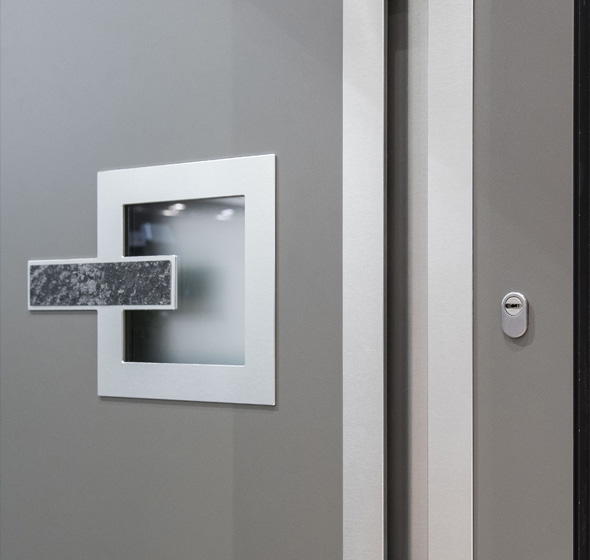 Zoom d'un détail de porte montrant un vitrage et détails d'insert pierre et alunox avec poignée intégrée porte d'entrée contemporaine Prestige AMCC